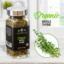 A glass jar of The Spice Lab Organic Whole Thyme from The Spice Lab rests on a kitchen counter beside a sprig of fresh thyme—ideal for infusing seasoning blends and bringing genuine flavor to French, Italian, and Mediterranean dishes. Text reads: Organic Whole Thyme.