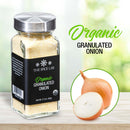 A jar of The Spice Lab Organic Granulated Onion, a true pantry staple, rests on a wooden surface next to a whole and a sliced onion, with “The Spice Lab Organic Granulated Onion” shown in green and black text beside the jar.