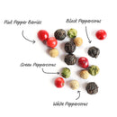 A medley of pink, black, green, and white peppercorns is scattered across a white background, each variety clearly labeled with handwritten text and arrows pointing out the pink pepper berries as well as the black, green, and white peppercorns—ideal for refilling your favorite grinder or experiencing the robust flavor of The Spice Lab Four Pepper Blend with Grinder 3-Pack by The Spice Lab.