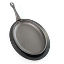 The Napoleon Grills Cast Iron Fajita Skillet with Removable Handle (56003) features superior heat retention, a black oval design, and comes with a matching wooden base, shown here on a white background.