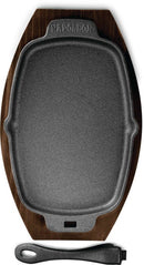 The Napoleon Grills Cast Iron Sizzle Platter (56008) features a porcelain-coated rectangular design with a wooden tray and detachable black handle—ideal for bringing your dish from grill to table.