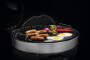 On a Napoleon Grills Cast Iron Reversible Griddle for 22 inch Charcoal Grills (56083), sausages, eggs, onions, peppers, and herbed butter sizzle on its porcelain-enameled surface with the lid open against a dramatic black background.