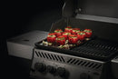 Stuffed tomatoes with herbs and cheese rest atop the Napoleon Enameled Cast Iron Reversible Griddle for Rogue® 425 by Napoleon Grills, shown on a grill with three knobs and a partially opened lid against a dark background.