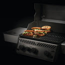 Four sandwiches with meat, cheese, and veggies are grilling on a Napoleon Enameled Cast Iron Reversible Griddle for Rogue® 425 by Napoleon Grills; dark grill marks pop against the bread on this outdoor accessory.