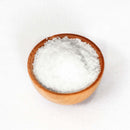 A small wooden bowl filled with coarse white The Spice Lab Hudson Valley New York Premium Gourmet Salt, placed on a plain white background.