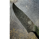 A close-up of the Spaceman Knives Gravity Series Chef Knife blade displays intricate wavy Damascus patterns and a round maker’s mark near the handle, with the partially visible textured handle by Spaceman Knives.