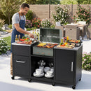 A person grills vegetables and skewers on the DirectDeals Outdoor Grill Table 59″ with Removable Shelves & Storage, surrounded by dishes and condiments on a patio with flowers and outdoor seating.