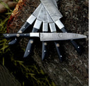 A Texan Knives 13" Handmade Damascus Steel Chef Knife with an epoxy resin handle and leather sheath is displayed fanned out on a tree stump, with grass in the background—perfect for trending culinary presentations.