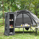 A gray tent and the DirectDeals Folding Camping Storage Cabinet with 3 Shelves and Carry Bag, along with food, a chair, and a table with cups and plates, are set up on grass in a wooded area.