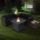 The DirectDeals 5 Piece Patio Furniture Set with 50000 BTU Propane Fire Pit Table features black cushions and a side table for drinks, creating an inviting outdoor entertaining space on the lawn at night.