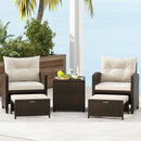 The DirectDeals 5 Pieces Patio Rattan Furniture with 2 Ottomans and Tempered Glass Coffee Table-Red creates a cozy outdoor seating area, perfect for relaxing and enjoying views of the ocean, palm trees, and greenery.