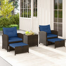 The DirectDeals 5 Pieces Patio Rattan Furniture with 2 Ottomans and Tempered Glass Coffee Table-Red creates a welcoming outdoor seating area on a light rug in front of a white house surrounded by greenery.