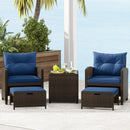 The DirectDeals 5 Pieces Patio Rattan Furniture with 2 Ottomans and Tempered Glass Coffee Table-Red creates a perfect outdoor conversation area on a patio by the ocean and palm trees.