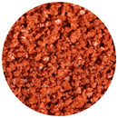 Close-up of coarse, reddish-orange granules inside a white circular border, reminiscent of colored salt crystals or decorative gravel. These medium grain crystals are typical of The Spice Lab Hawaiian Red Alaea Sea Salt, known for its earthy flavor and distinctive appearance.