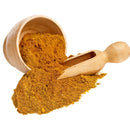 A wooden bowl tipped over, spilling The Spice Lab Organic Indian Curry Powder onto a surface, with a wooden scoop resting in the aromatic pile of spice.