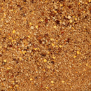 A close-up of a textured, brown spice blend with visible yellow and red flakes—likely crushed chili and other seasonings or seeds—spread evenly across the surface; this appears to be an intense extreme heat seasoning such as The Spice Lab’s Smoked Ghost Pepper Sea Salt.