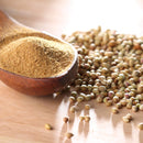 A wooden spoon filled with The Spice Lab Organic Ground Coriander rests on a wooden surface beside a pile of whole coriander seeds, making it perfect for adding warm, aromatic flavor to Indian dishes and spice blends.