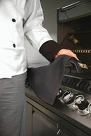 A chef in a white jacket and gray pants uses the Napoleon Grills Grill Towel (62150) to clean or adjust controls on a stainless steel oven or grill.
