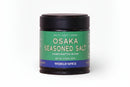 A 2.33-ounce (66g) jar of World Spice Osaka Seasoned Salt, packaged with a green label detailing its nutty, salty, umami flavors and handcrafted quality. This Japanese seasoning salt from World Spice blends rich flavors with the distinctive savoriness of seaweed salt for an authentic taste experience.