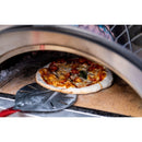 A pizza with melted cheese and toppings is being taken out of a wood-fired oven using the WPPO 7" Round Turning Pizza Peel With Break Down Handle from WPPO LLC Direct.