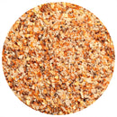 A close-up, top-down view of a round mound of The Spice Lab Classic Steakhouse Steak Seasoning by The Spice Lab, showcasing its coarse blend with orange, yellow, and brown granules—possibly a mix of salt, dried herbs, and crushed seeds.
