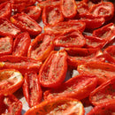 Halved tomatoes with herb seasoning blends and The Spice Lab Organic Whole Thyme sprinkled on top, spread out on a surface and sun-drying in bright sunlight.