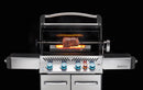A Napoleon Grills Prestige® 500 is grilling a large piece of meat using the Napoleon Commercial Grade Rotisserie Kit (69231), with blue control knobs and bright flames in the background.
