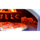 A pizza baking inside the WPPO Karma 25 Wood-Fired Oven by WPPO LLC Direct, with flames visible in the background and melted cheese bubbling on the crust.