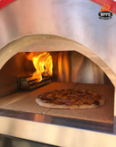A pizza with toppings bakes on a stone inside the WPPO Traditional 25" Dual Fueled Pizza Oven With Gas Attachment—Wood and Gas Powered, by WPPO LLC Direct, with visible flames in the back and a WPPO logo displayed in the upper right corner.