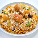 A plate of chicken biryani with colorful rice, tender chicken pieces, potatoes, green chilies, and garnished with thinly sliced white onions and The Spice Lab Organic Cinnamon Sticks by The Spice Lab for an aromatic finish.