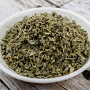 A white bowl filled with The Spice Lab Whole Marjoram sits on a rustic wooden surface, perfect for enhancing seasoning blends or use as a bulk foodservice spice.
