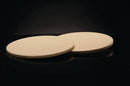 Two round, flat, light beige Napoleon Grills 10 Inch Personal Sized Pizza/Baking Stones (Set of 2, model 70000) are placed side by side on a shiny black surface—perfect for creating crispy homemade pizza.