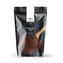 A black, resealable bag of The Spice Lab Ancho Chili + Coffee Rub, featuring the product name and brand on the label and accompanied by a wooden spoon filled with the spice blend. Ideal for use as a BBQ seasoning or in bulk foodservice applications, the upright bag is displayed against a white background.