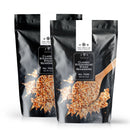 Two black pouches of The Spice Lab Classic Steakhouse Steak Seasoning by The Spice Lab—an outstanding steakhouse blend perfect for any cut of meat—are displayed side by side against a white background, each featuring an image of the seasoning and a wooden spoon.