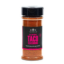 A clear plastic jar of The Spice Lab All-Natural Taco Seasoning with a black flip-top lid and a black label featuring bright pink text. The 5 oz (141g) jar contains all-natural, smoky taco seasoning.