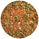 A close-up of The Spice Lab Island Jerk Seasoning by The Spice Lab showcases a vibrant blend of dried green herbs, red pepper flakes, and ground spices within a circular frame. This bold mix is the perfect grill seasoning, capturing the essence of classic Caribbean jerk flavors.