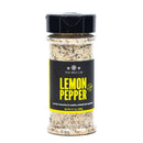A clear plastic spice shaker from The Spice Lab Cooking Essentials Seasoning Set, featuring a black and yellow label and filled with a coarse seasoning blend, is displayed against a white background—an essential addition to any grilling spices collection.