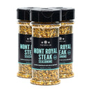 Three bottles of The Spice Lab Mont Royal Steak Seasoning by The Spice Lab, featuring black lids, light blue and black labels, and filled with a coarse seasoning blend, are displayed against a white background.