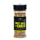 A clear spice jar from The Spice Lab labeled “Sweet Basil & Garlic Seasoning,” featuring a black lid and black label, filled with a flavorful seasoning blend.