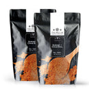 Two black resealable pouches of The Spice Lab Shrimp + Crab Boil Seasoning, each labeled 2 lbs, are shown next to a wooden spoon filled with the zesty seasoning featured on the front of the packaging.