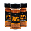 Three bottles of The Spice Lab Shrimp + Crab Boil Seasoning, a reddish seafood blend with medium heat from The Spice Lab, are shown in clear plastic containers topped with black lids and adorned with black labels. The bottles are neatly arranged side by side.