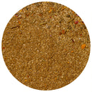A close-up, top-down view of a round pile of The Spice Lab Nom Nom Paleo Magic Mushroom Powder by The Spice Lab, showcasing its blend of ground spices and herbs—including umami seasoning with visible small granular and flaky pieces in various brown and greenish tones.