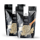 Two black resealable pouches of The Spice Lab Lemon Pepper + Thyme Seasoning—a zesty citrus and herb blend from The Spice Lab, ideal for chicken—are displayed on a white background, each accompanied by a wooden spoon scooping the fragrant seasoning.