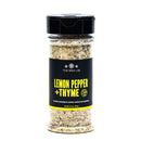 A clear spice jar labeled “The Spice Lab Lemon Pepper + Thyme Seasoning” by The Spice Lab, featuring a black lid and black label, filled with a zesty blend of lemon pepper and thyme seasonings that’s perfect for poultry, seafood, and vegetables.
