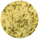 A close-up view of The Spice Lab Garlic Salt Seasoning by The Spice Lab, featuring yellow granules and scattered green herb flakes, displayed in a circular frame on a white background.
