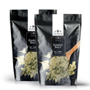 Two black resealable bags of The Spice Lab Garlic Salt Seasoning are displayed, with packaging that features a wooden spoon and garlic salt. This savory seasoning from The Spice Lab is infused with rich garlic flavor, making it ideal for enhancing dishes such as garlic bread. Each bag has a net weight of 2 lbs.