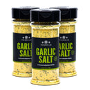Three bottles of The Spice Lab Garlic Salt Seasoning by The Spice Lab are grouped together on a white surface, their black caps and green-labeled packaging visible, ready to bring savory garlic flavor to your favorite dishes.