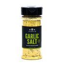 A clear spice jar labeled The Spice Lab Garlic Salt Seasoning, from The Spice Lab brand, filled with yellow and green garlic salt seasoning. It features a black lid and a black label with green and white text, perfect for adding a savory garlic flavor to your dishes.
