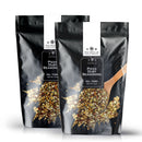 Two black pouches labeled The Spice Lab Pizza Dust Seasoning feature an image of a wooden spoon scooping the savory blend. The front highlights the brand, The Spice Lab, and the weight: 2 lbs, encapsulating pizza-inspired flavor in every sprinkle.