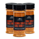 Three bottles of The Spice Lab Brown Sugar Chili Rub are arranged in a triangle, each with a clear label showcasing the orange-red seasoning inside, ready to infuse your next cookout with bold, smoky BBQ flavor.